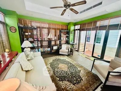 Charming living room with vibrant green walls, cozy seating, and abundant natural light from large windows.