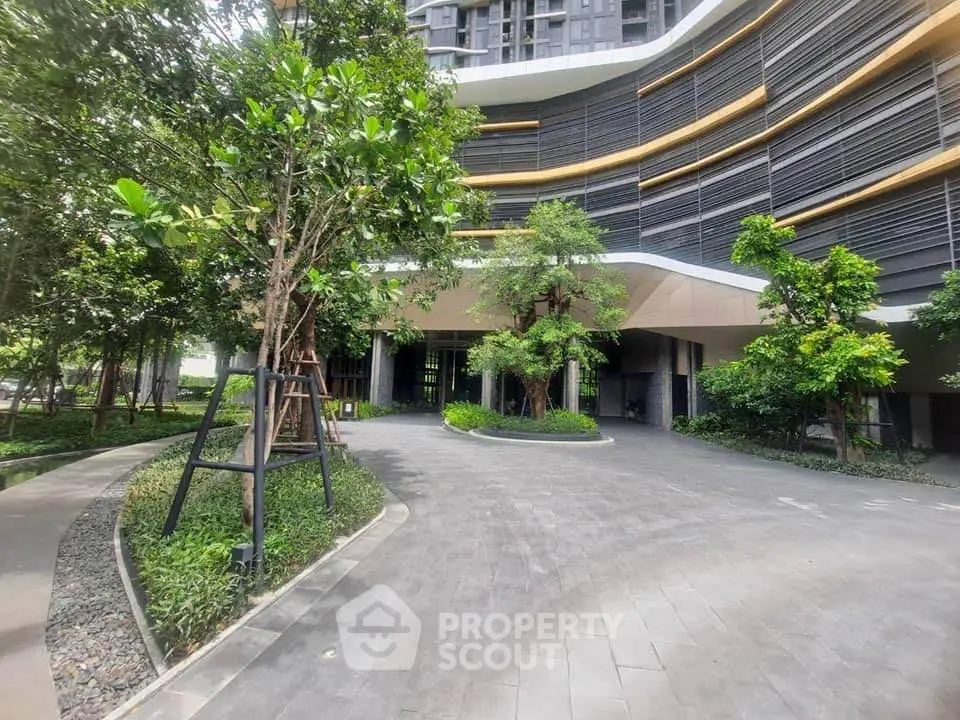 Modern building entrance with lush greenery and sleek architectural design