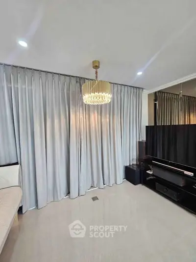 Elegant living room with modern chandelier and floor-to-ceiling curtains