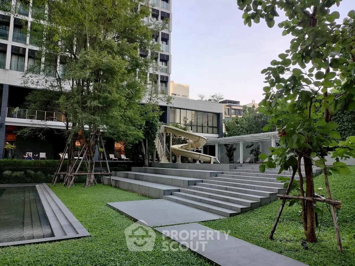 Luxurious modern building with lush garden and unique outdoor slide feature.