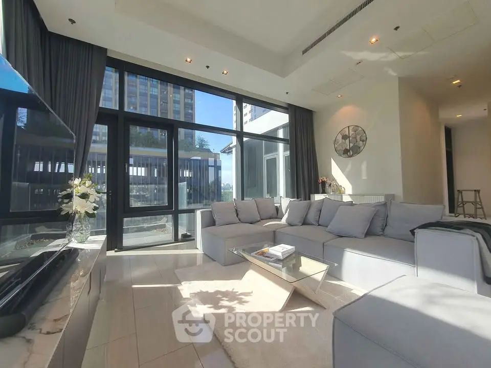 Luxurious modern living room with floor-to-ceiling windows and elegant decor in a high-rise apartment.