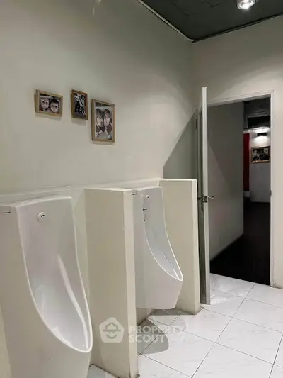Modern restroom with urinals and framed wall art in a commercial building.