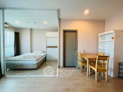Modern studio apartment with cozy bedroom and dining area, featuring wooden flooring and ample natural light.
