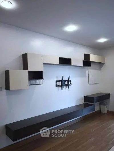 Modern minimalist living room with sleek wall-mounted storage and wooden flooring.