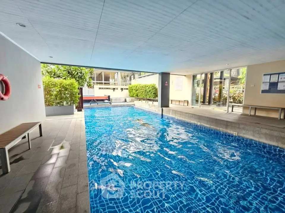 Luxurious indoor swimming pool with modern design and ample natural light in a high-end residential complex.