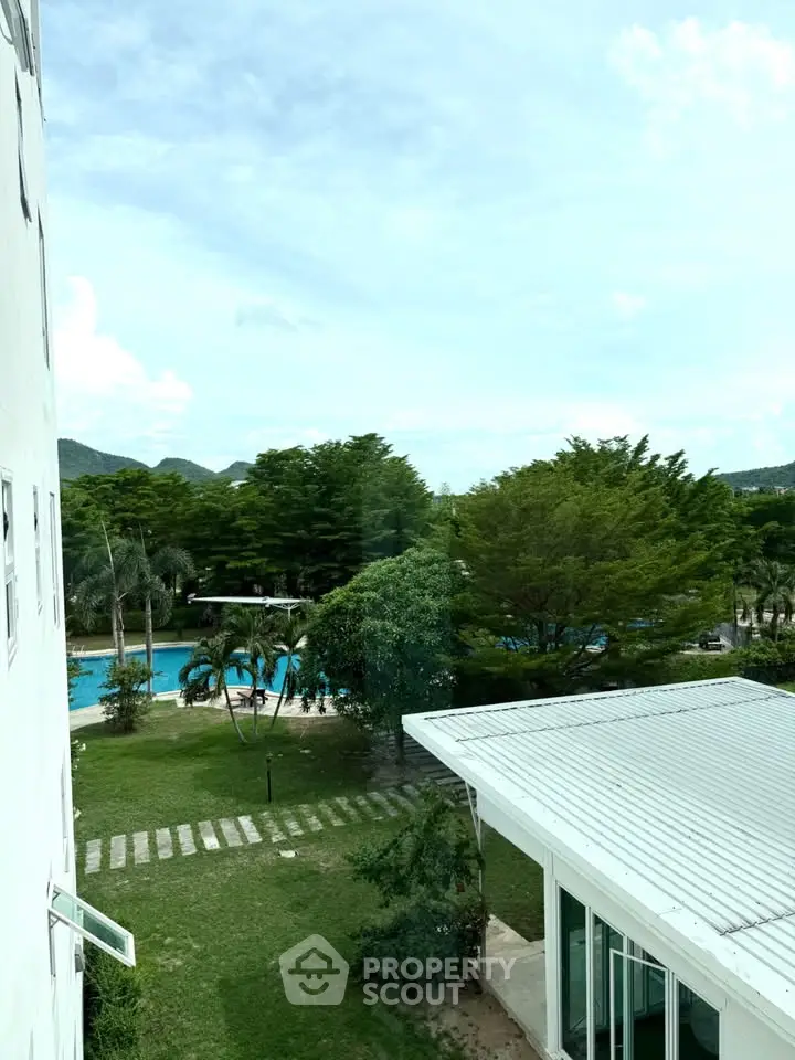 Stunning view of lush greenery and pool from a modern building balcony.