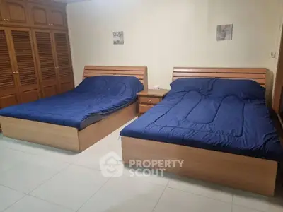 Spacious bedroom with two double beds and wooden wardrobes, ideal for family living.