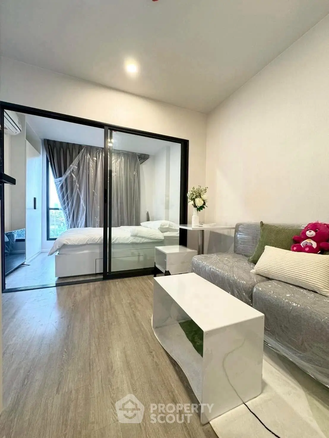 Modern living room with sliding glass doors leading to a cozy bedroom, featuring stylish decor and natural light.