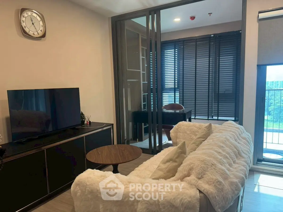Modern living room with cozy sofa, TV, and balcony view