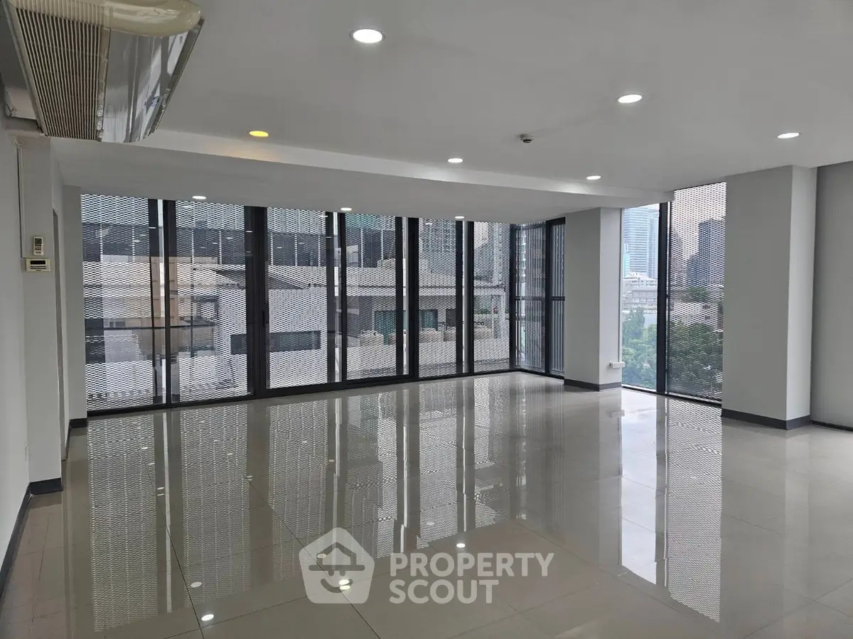 Spacious modern living room with floor-to-ceiling windows and city view.
