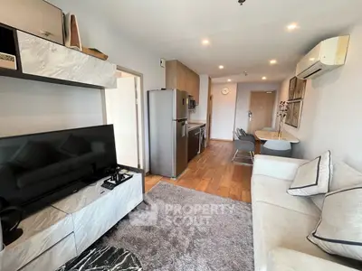 Modern open-layout living room with kitchen, featuring sleek furniture and wooden flooring.