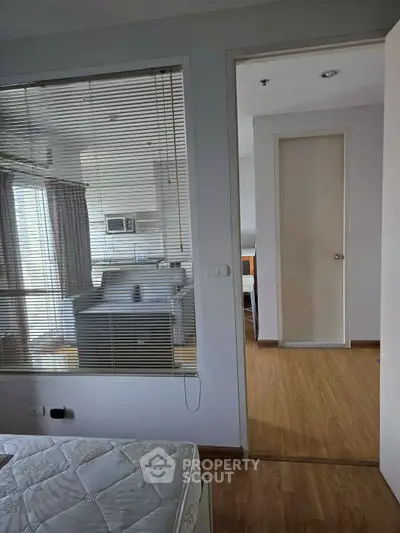 Modern apartment interior with wooden flooring and large windows for natural light.