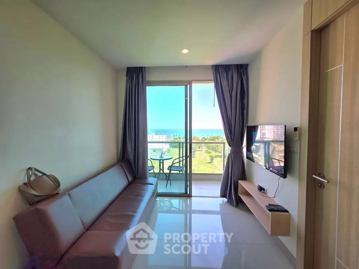 Modern living room with balcony and scenic view, featuring sleek furniture and natural light.