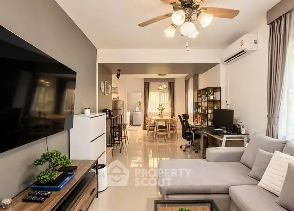 Spacious modern living room with stylish decor and open layout, featuring a cozy sofa and large TV.