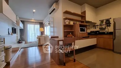 Modern open-layout living room and kitchen with stylish wooden furniture and natural light.