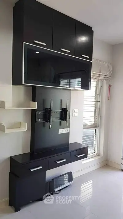 Modern living room with sleek black entertainment unit and large window