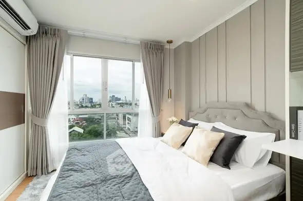 Luxurious bedroom with city view, elegant decor, and ample natural light.