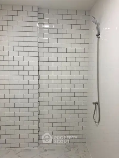 Modern bathroom with sleek white subway tiles and minimalist shower design.