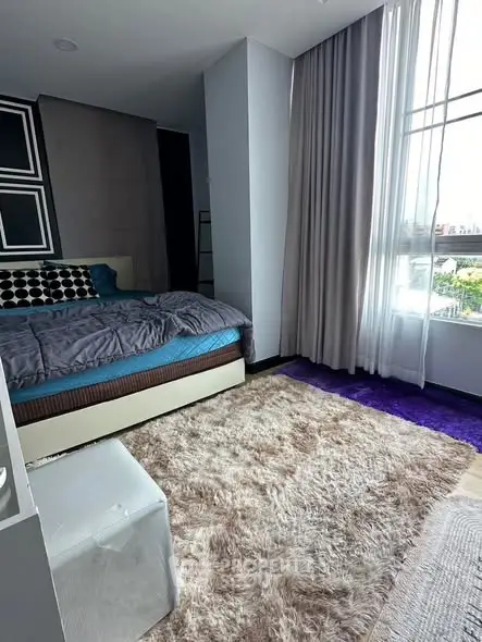 Spacious bedroom with large window and plush carpet in modern apartment
