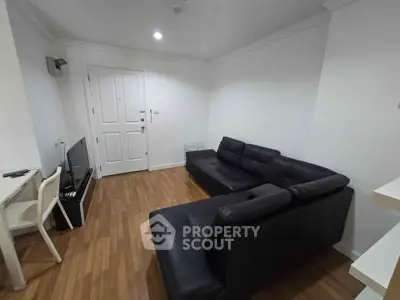 Modern living room with sleek black leather sofa and wooden flooring