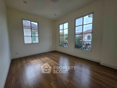 Spacious empty room with large windows and wooden flooring, perfect for customization.
