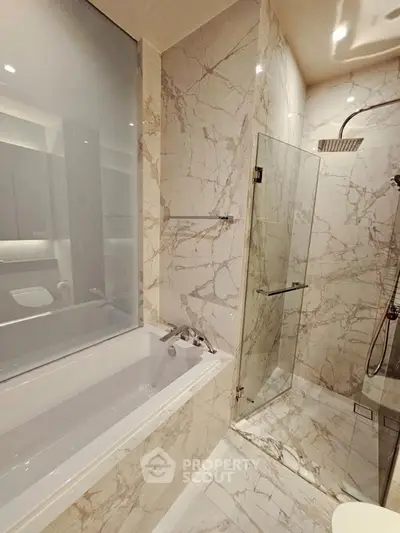 Luxurious marble bathroom with bathtub and glass shower enclosure
