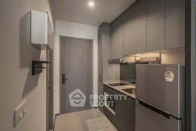 Modern compact kitchen with sleek cabinetry and stainless steel appliances in a stylish apartment.