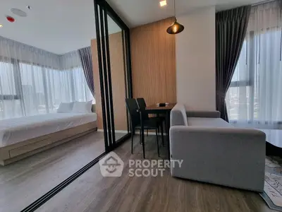 Modern studio apartment with stylish decor, featuring a cozy living area and a separate bedroom with large windows.