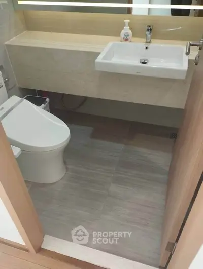 Modern bathroom with sleek fixtures and neutral tones, featuring a stylish sink and toilet.