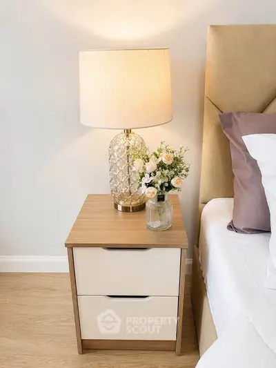 Elegant bedroom nightstand with lamp and floral decor, showcasing modern interior design.