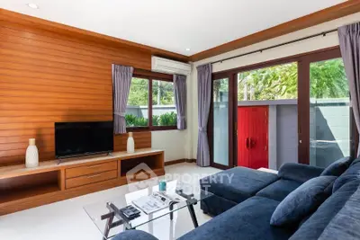 Modern living room with sleek furniture and large windows offering natural light and garden view.