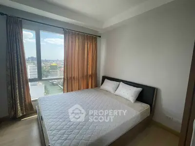 Bright bedroom with large window and city view, featuring a comfortable bed and elegant curtains.
