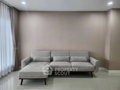Spacious living room with modern gray sectional sofa and elegant curtains