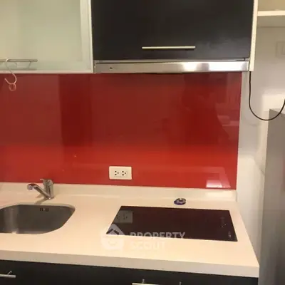 Modern kitchen with sleek red backsplash and electric cooktop