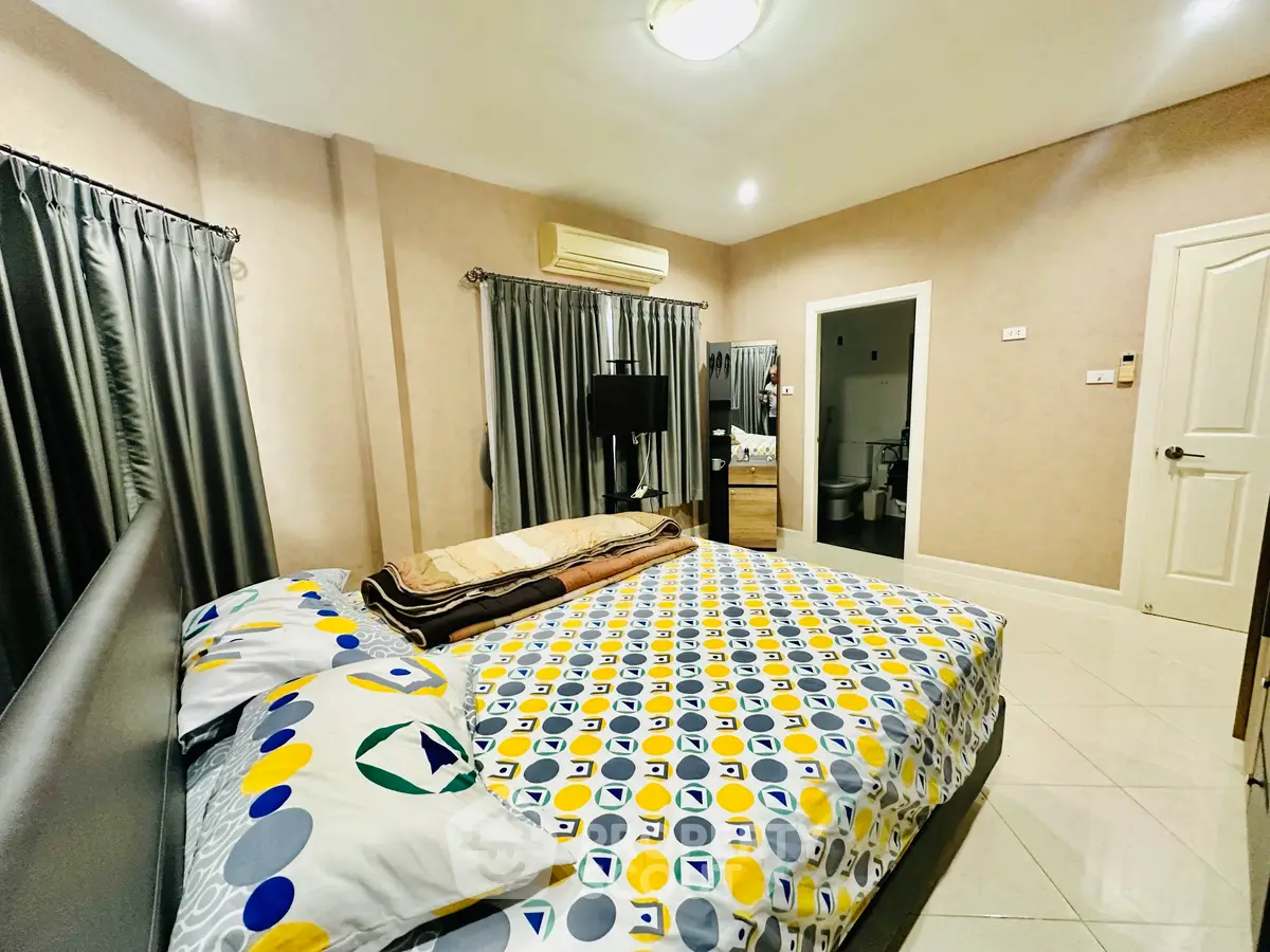 Spacious bedroom with modern decor and ensuite bathroom in a cozy home.