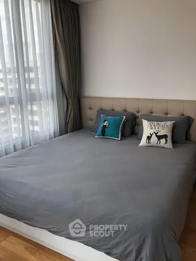 Spacious bedroom with large window and stylish decor in modern apartment.