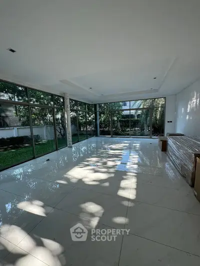 Spacious living room with large windows offering garden views and abundant natural light.