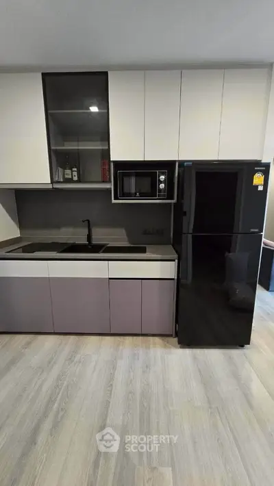 Modern kitchen with sleek cabinetry and black appliances in a stylish apartment.