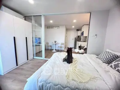 Modern bedroom with open layout to dining area, featuring sleek furniture and cozy decor.