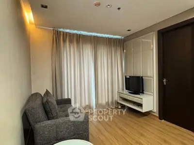 Cozy living room with modern sofa and TV, featuring elegant wooden flooring and soft lighting.