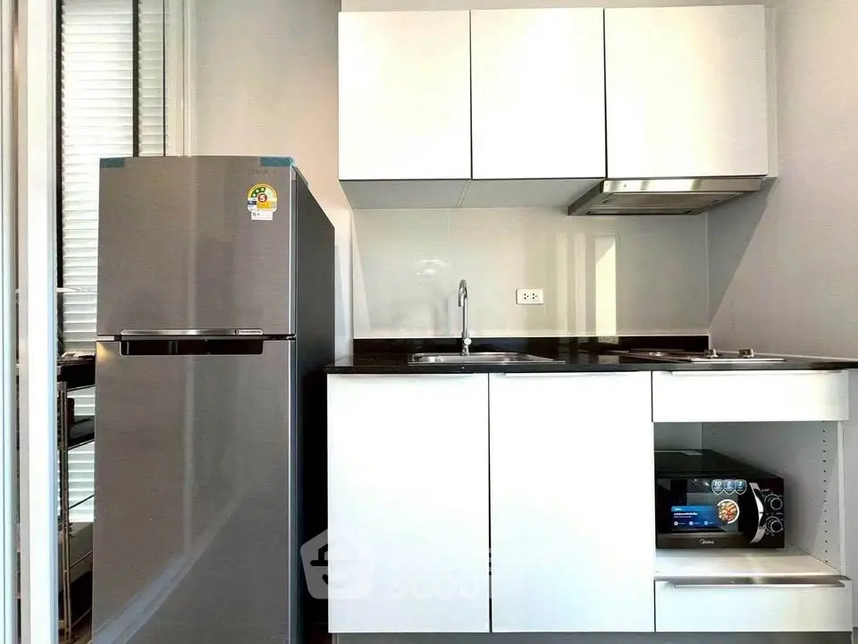 Modern compact kitchen with stainless steel fridge and sleek cabinetry