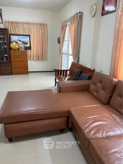 Spacious living room with leather sofa and natural light, perfect for relaxation and entertaining.