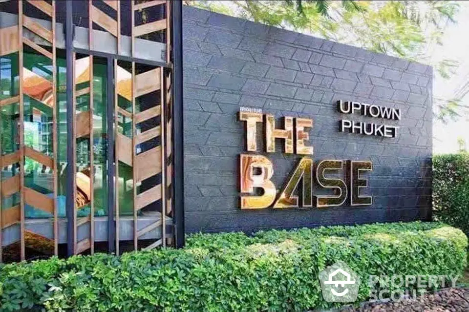 Modern exterior signage of The Base Uptown Phuket with lush greenery.