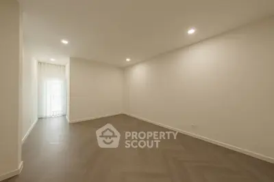 Spacious empty room with elegant herringbone flooring and soft lighting, perfect for customization.