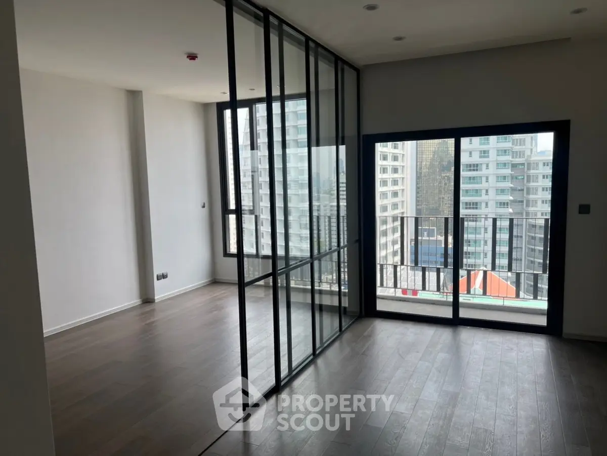 Modern apartment with floor-to-ceiling windows and city view, featuring sleek glass partitions.