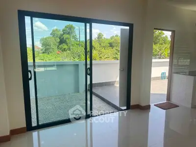 Spacious room with sliding glass doors leading to a private balcony with lush green views.