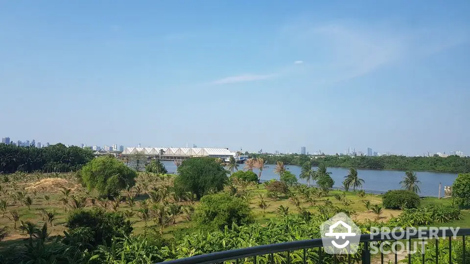 Scenic river view from a balcony with lush greenery and city skyline