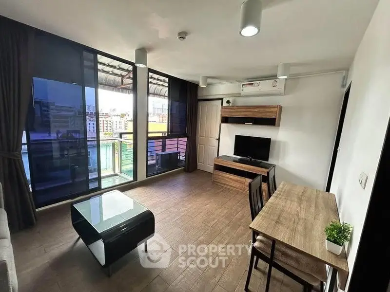 Modern living room with balcony view, featuring sleek furniture and natural light.