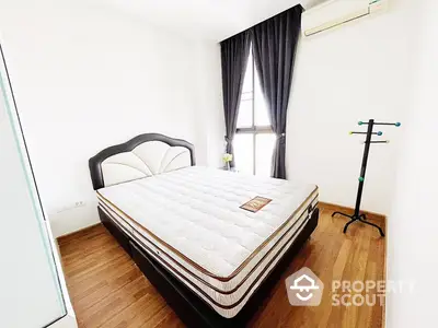 Spacious and well-lit bedroom with a large comfortable bed, elegant dark curtains, and sleek hardwood flooring, perfect for restful nights.