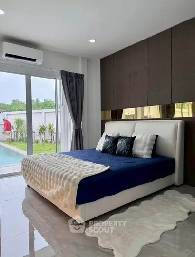 Luxurious bedroom with pool view, modern decor, and plush bedding for ultimate comfort.